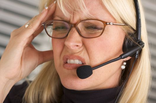 Businesswoman with phone headset show signs of having a headache.