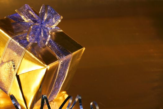 Elegant gold present with blue ribbons on  gold background.