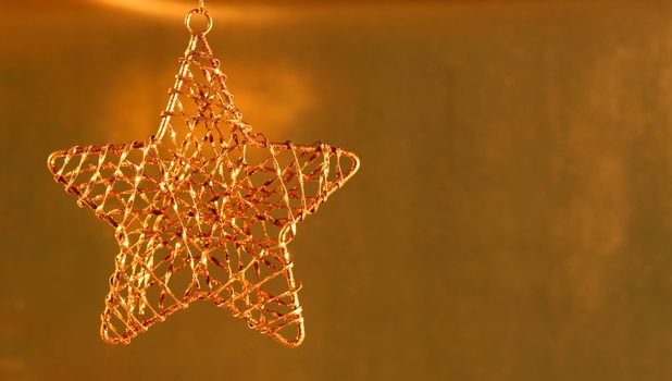 Gold star ornament on gold shiny background.