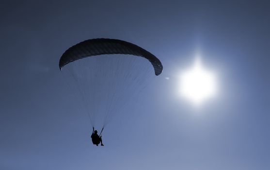 Paraglider flying agains the sun on sunset