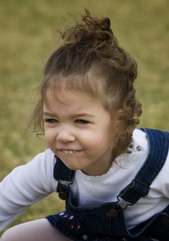 Young girl on grass with a funny smile.