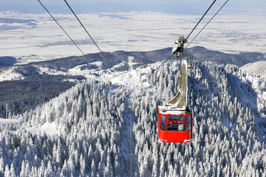 Winter landscape with a red cable car.