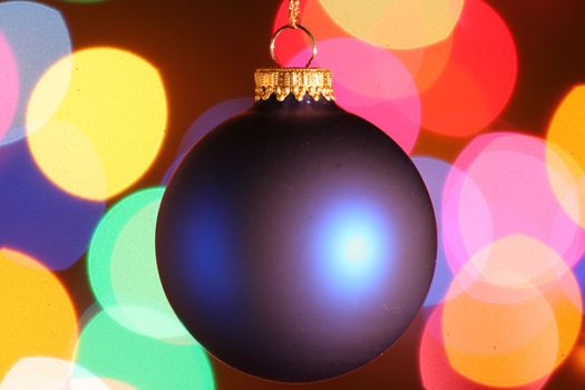 Blue frosted Christmas ornament with colorful lights in background.