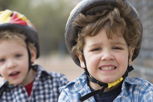 Two little boys in bicycle helmets - one boy looks concerned
