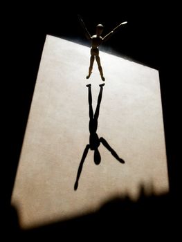 Artist's model with heavy backlight and arms outstretched throws a long shadow.