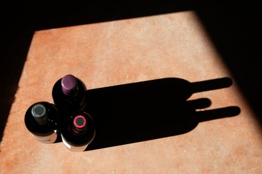 Wine bottels with heavy side-light and long, dramatic shadow. 