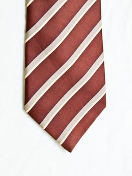 A rolled up striped brown and white tie isolated on white background.