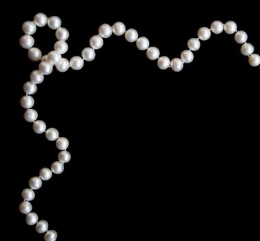 White pearls on the black silk as background 