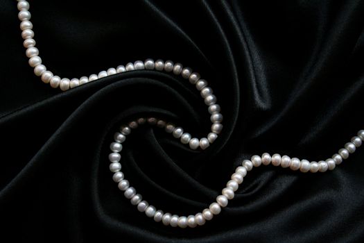 White pearls on the black velvet background 
