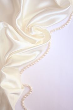 White pearls on the white silk as wedding background 