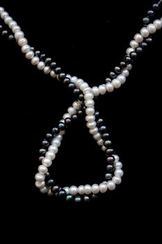 White and black pearls on a black velvet background 