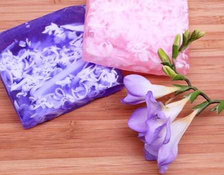 Lilac and pink soap with flower on wooden background in a spa composition 