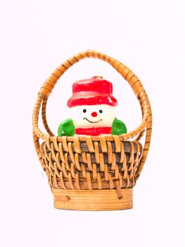 A christmas snow doll candle and a yellow wicker basket isolated on white background