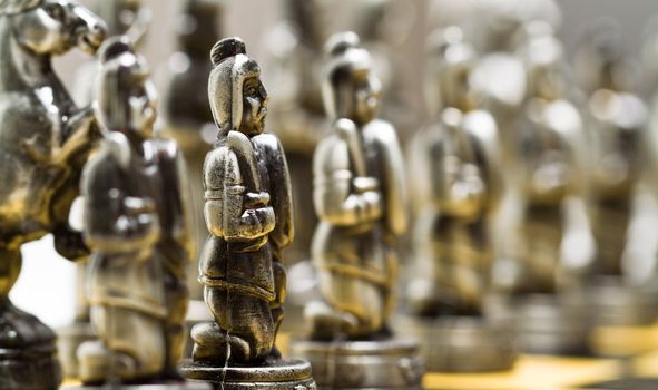 Silver chess pieces on a checkerboard blurry background