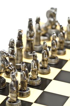 silver chess pieces on a checkerboard with white background