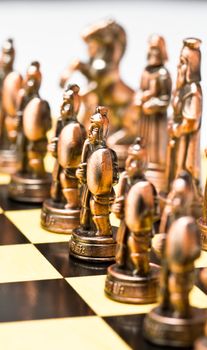 close up of a brass chess piece on a checkerboard in portrait orientation