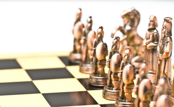 close up of a brass chess piece on a checkerboard with white background