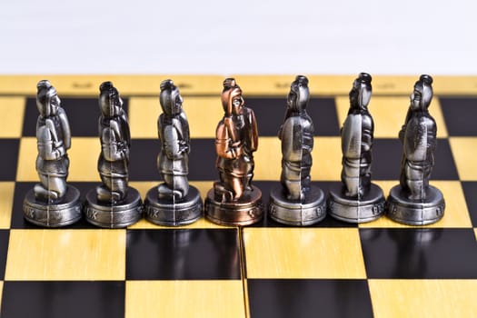 a brass pawn piece among the silver pieces on a checker board