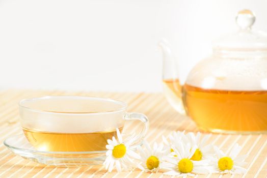 A teacup and a teapot with herbal chamomile tea