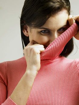 Woman covering face with turtleneck looking at the camera