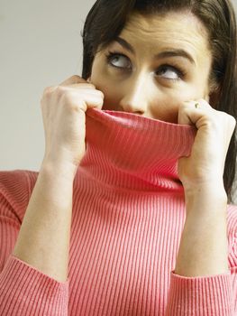 Woman covering face with turtleneck looking at the camera