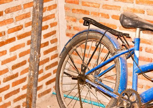 Old bicycle laid against the side of a brick wall.