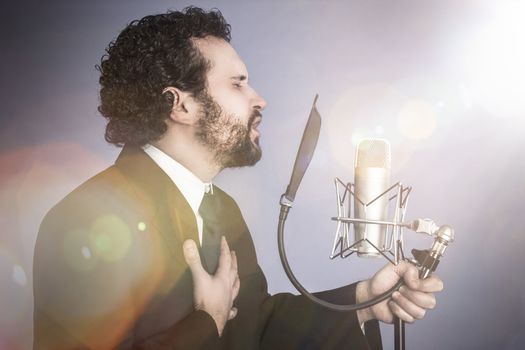 singing man with black suit and microphone on background with red curtain