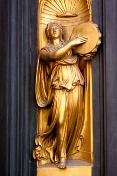 A bronaze dascer with tambourine on the church door
