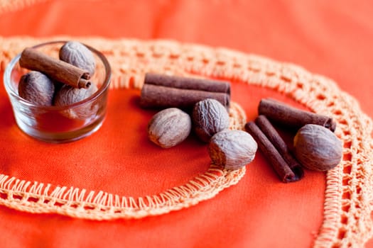 Several nuts and cinnamons on two orange napkins on a wood table
