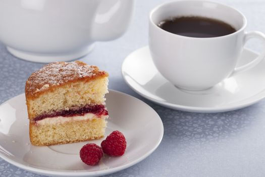 A cup of tea served with fresh victoria sponge cake