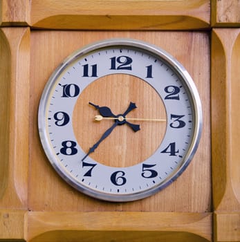 Closeup of clock in wooden box showing twentyseven past nine.