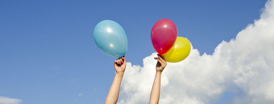 girl hands holding balloons on cloudy sky backgrounds