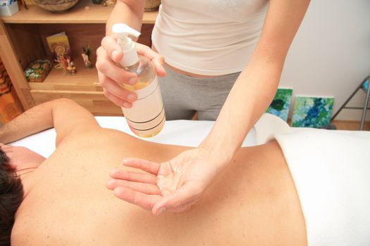 A female masseur preparing her hand with oil for a back massage