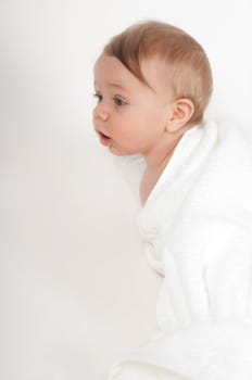 Cute little boy in white blanket  in studio