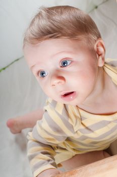 Little cute baby boy in striped clothes on the bed