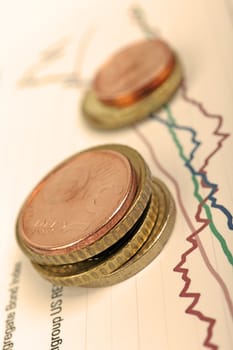 Euro coins laying on financial graph, selective focus, warm filter.