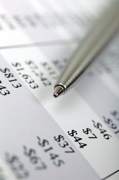 Macro of steel pen laying on printed financial report.