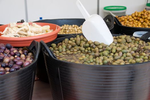 Different sorts of olives in big black barrels