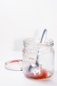 Empty marmalade jar and spoon isolated in studio