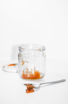 Empty marmalade jar and spoon isolated in studio