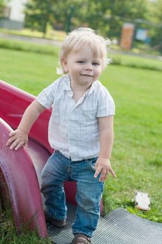 The little boy standing near red playground slide