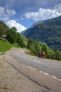 Cyclists on road among swiss alps, Europe.
