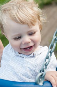 Happy little boy swinging on a swing