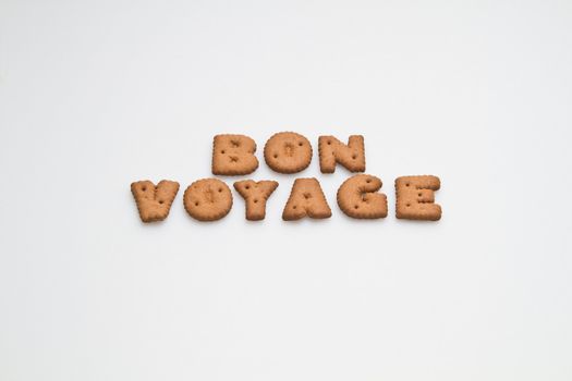 The phrase bon voyage made by brown biscuits arrangement on white surface