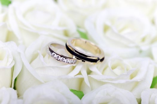 Two wedding rings on white roses bouquet.