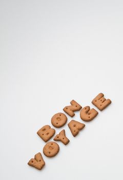 the phrase bon voyage made by brown biscuits slanting arrangement on white surface portrait orientation