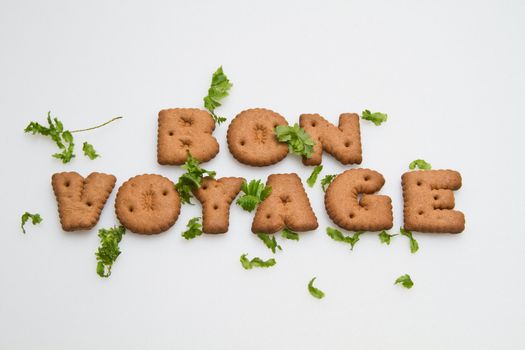 Bon Voyage phrase by brown biscuits and leaves on white surface