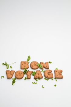 Bon Voyage phrase by brown biscuits and leaves on white surface in portrait orientation