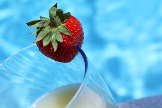 cocktail with strawberry standing by the poolside