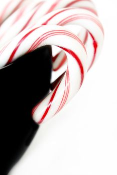 Candy canes in a black dish isolated on white.  Used a shallow depth of field with selective focus.